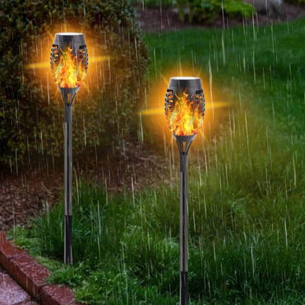 2-Pack Outdoor Solar Flame Lights for Courtyard Lawn glowing flaming LED torches on stakes in rainy garden pathway