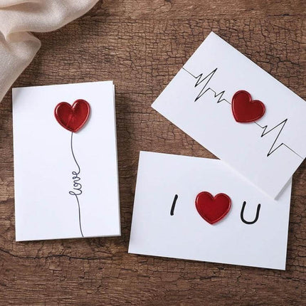 3D Heart Valentine Day Greeting Card With Envelopes showing three white cards with red 3D heart accents on wooden background