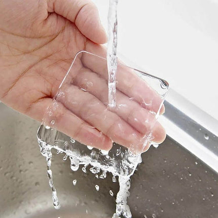 4 Pack Transparent Washing Machine Silicone Pads For Vibration Reduction - clear self-adhesive silicone pad being rinsed in hand, protects floors and reduces vibration