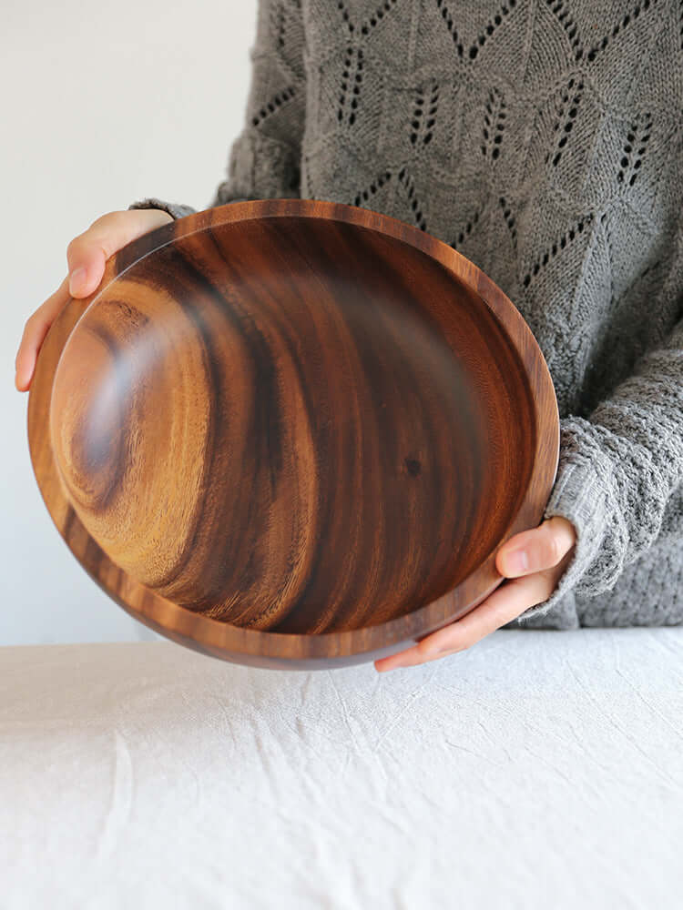 Handcrafted acacia wood bowl being held, showcasing its elegant natural grain for enhanced dining and tableware.