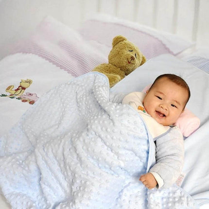 Baby Double Layer Knitted Fleece Blanket For Cozy Snuggles covering smiling baby in crib with plush teddy
