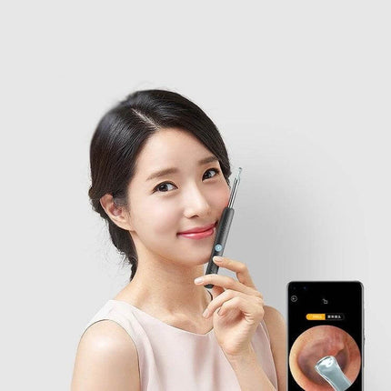 Bebird Endoscope Ear Cleaning Tool Black for Home Use held by woman with smartphone app showing ear canal view