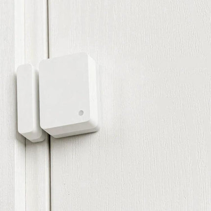 Xiaomi Intelligent Mini Door and Window Sensor for Home Security mounted on white door frame, compact magnetic sensor sending real-time alerts