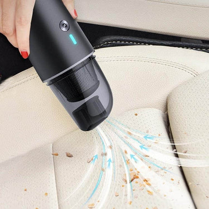 Navy Blue Wireless Handheld Vacuum Cleaner For Car And Home being used to vacuum crumbs from a beige car seat