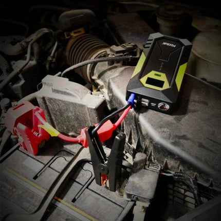 FOXSUR Portable Emergency Car Jump Starter Power Supply connected to car battery with clamps on engine bay