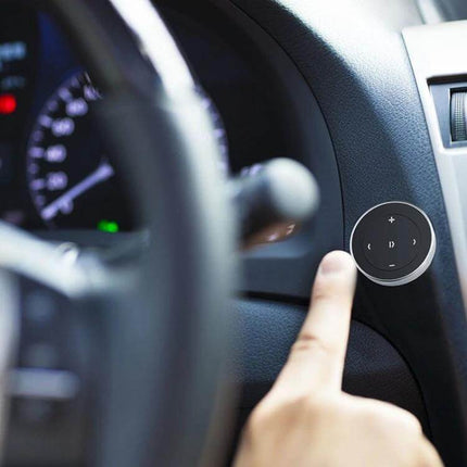Car Wireless Bluetooth Steering Wheel Music Controller Black mounted on car dash near steering wheel with finger pressing play button