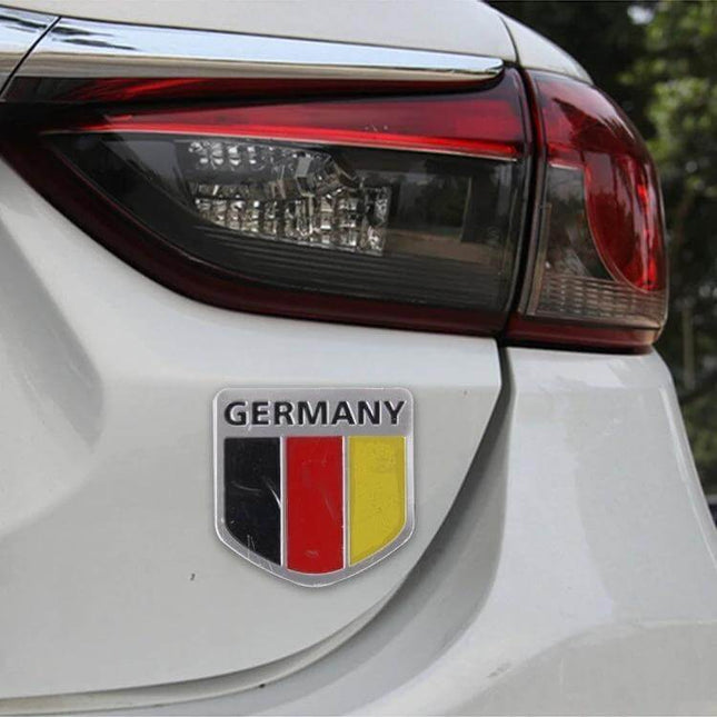 Germany Flag Style Metal Car Sticker for Vehicle Protection applied to white car rear near taillight, metal shield showing black red yellow stripes
