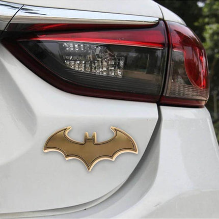 Bat-Shaped Shining Metal Decal for Everyday Car Styling on white car trunk near taillight, gold bat emblem for subtle vehicle personalization
