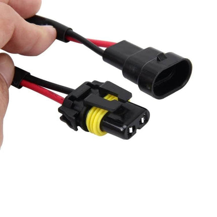 2-Pack HID Canbus Decoder For Cars - Anti-Flicker Adapters showing black and red wired anti-flicker connectors held by hand