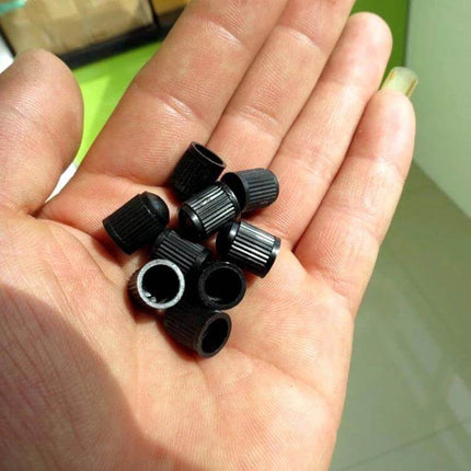 Black Rubber Valve Caps for Car and Bicycle Tires, 200 Pack held in hand showing size and ribbed grip to protect valve stems from dust and moisture
