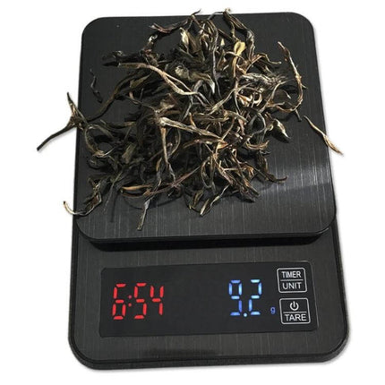 Coffee Scale With Timing For Everyday Kitchen Use - black digital scale showing 9.2g and timer with dried tea leaves on platform