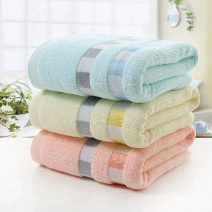 Cotton Plain Bath Towel 140x70 For Daily Bathroom Use - soft plain cotton towel folded in pastel blue, yellow and peach for everyday use