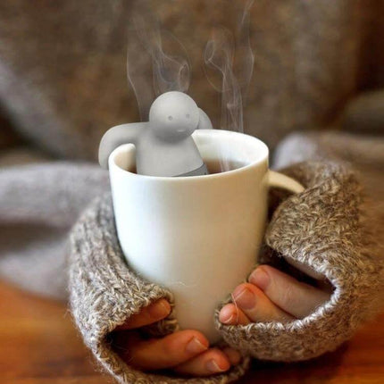 Cute Mr Tea Infuser Compact Silicone Tea Strainer For Everyday Tea - gray silicone tea infuser steeping in steaming white mug held with cozy sweater