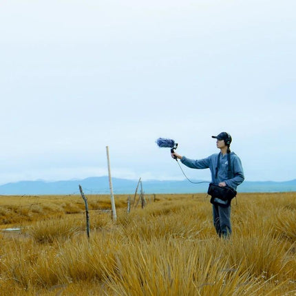 Person using Deity Shotgun Microphone for Daily Vlogging and Interviews outdoors capturing clear audio with windscreen and headphones