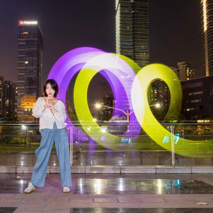 LUXCeO P7RGB Pro Handheld LED Light for Photo and Video Sessions illuminating colorful light trails behind model in urban night shoot