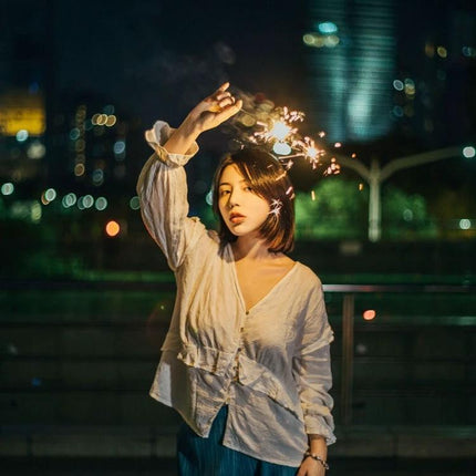 LUXCeO P7RGB Pro Handheld LED Light for Photo and Video Sessions - model holding sparkler at night with city bokeh lighting