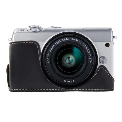 PU Leather Protective Half Case for Canon Cameras shown on silver Canon EOS M100 with lens attached, black synthetic leather half-cover protecting body