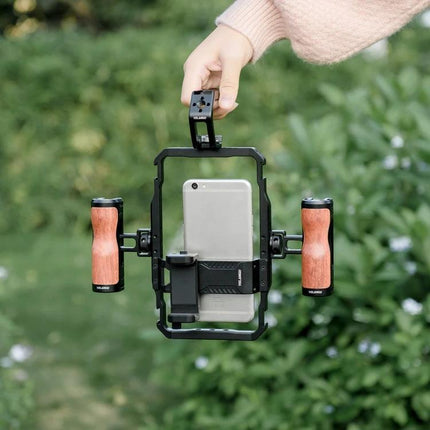 YELANGU Handheld Video Stabilizer Top Handle for Camera Cages held outdoors with wooden grips and smartphone mounted