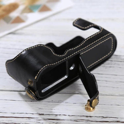 PU Leather Protective Half Case for Fujifilm X-E3 Camera in black synthetic leather with white stitching, shown open on wooden surface