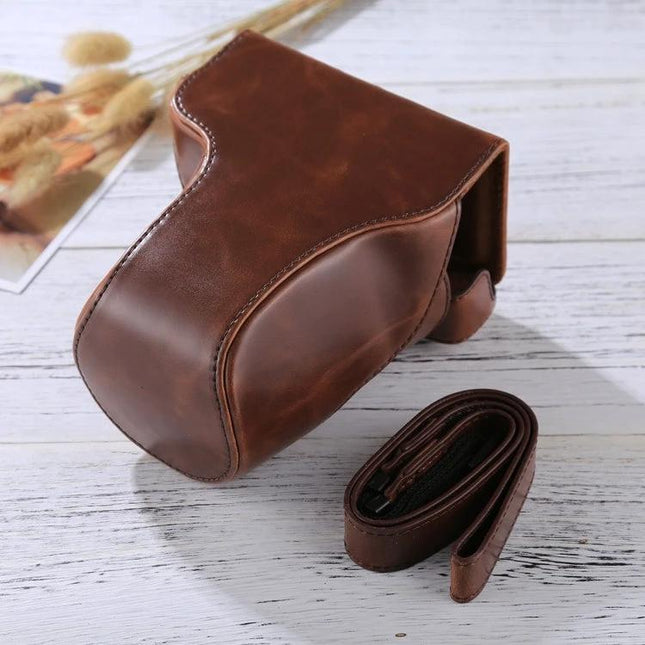 PU Leather Protective Case for Canon EOS M6 with 18-150mm Lens shown in brown leather with detachable shoulder strap, protective cover on white wood surface