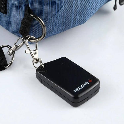 Wireless Anti-Lost Alarm for Tracking Everyday Items small black receiver keychain attached to a blue bag, labeled RECEIVE, alert device for keys and bags