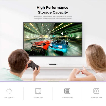Xiaomi 4K HDR Google TV Streaming Media Player connected below a TV showing 4K racing game, family using controller and voice remote