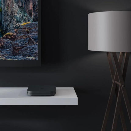 Xiaomi 4K HDR Google TV Streaming Media Player on shelf below TV, compact streaming device for 4K HDR family entertainment