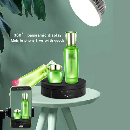USB Electric Rotating Turntable for Photography Displays showing green skincare bottles on a rotating platform under studio light