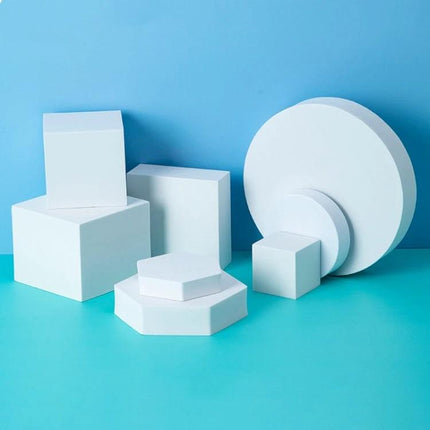 Solid Color Geometric Shapes Polymer Foam Props for Photography arranged in white cubes, hexagon and circles on blue backdrop for clean product staging