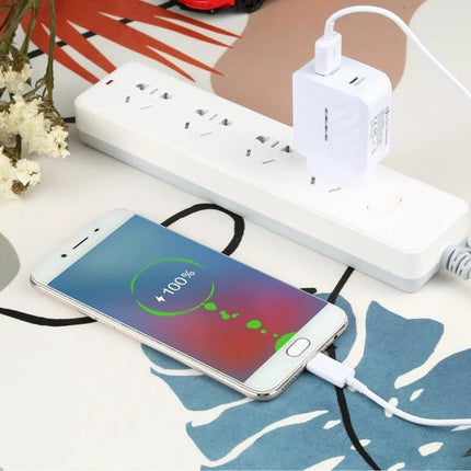 Essential Travel Charger for Devices During Daily Commutes - dual-port white charger plugged into power strip charging smartphone at 100%