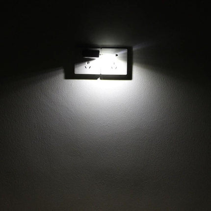 Compact USB Light for Nighttime Reading and Travel Essentials plugged into wall outlet casting focused beam on dark room wall
