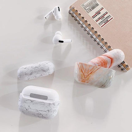 Marble Texture Protective Case for Everyday AirPods Use showing white and orange marble AirPods cases with earbuds and notebook