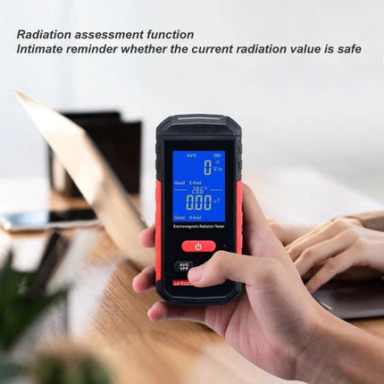 Wintact Household Electromagnetic Radiation Testing Device handheld meter showing blue screen measuring radiation near laptop and hands