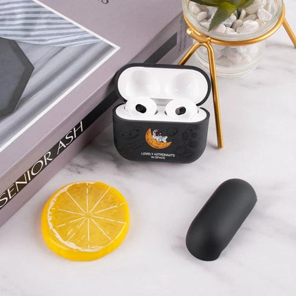 A Simple Protective Case for AirPods in Daily Use - black silicone case with cute astronaut design next to AirPods on marble surface