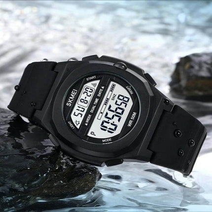 SKMEI Electronic Watch with Silicone Strap for Daily Timekeeping black digital watch on rocks by water showing dual time stopwatch and silicone strap
