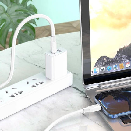 Hoco Charging Cable for Daily Phone Power Needs — 1m white cable charging phone and laptop on desk