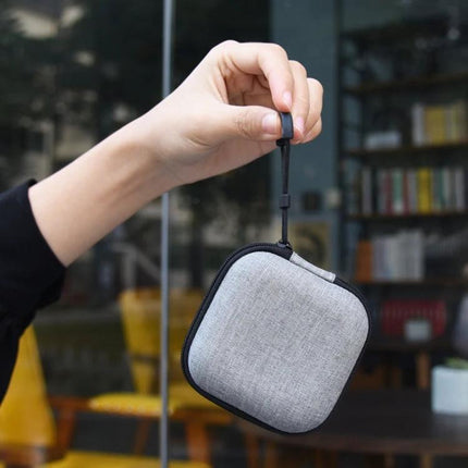 Essential Silicone Set for Everyday Earphone Protection and Travel - gray silicone earphone case with strap being held over cafe background