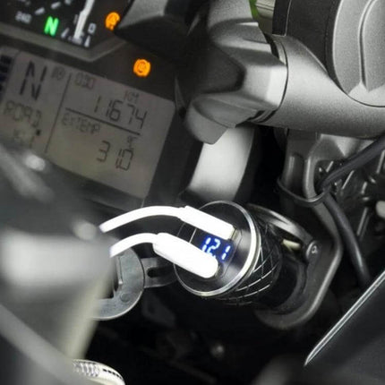 Motorcycle USB Charger With Voltmeter For Onboard Power Monitoring plugged into bike socket showing 12.1V digital readout and dual USB cables