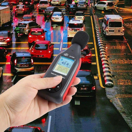 Benetech Decibel Meter for Everyday Sound Level Monitoring held near busy city traffic measuring 42.6 dB
