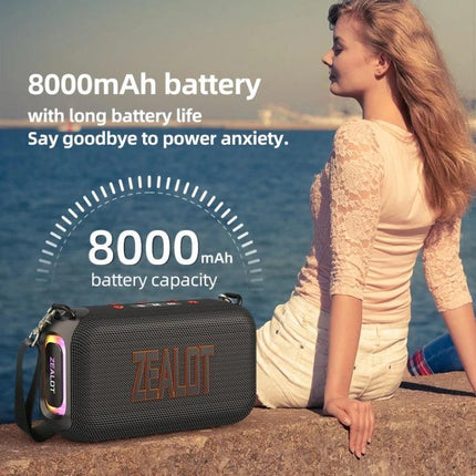 Zealot Portable Bluetooth Speaker For Travel And Outdoor Use showing 8000mAh battery by ocean with woman sitting