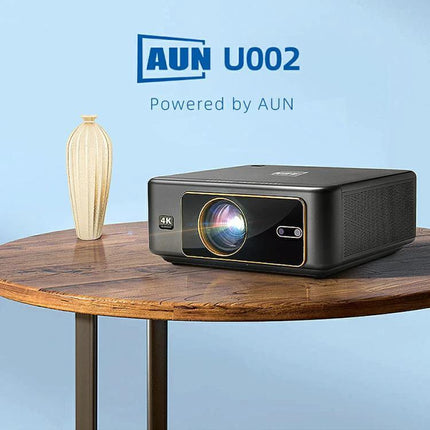 AUN Home Theater Projector with Smart Features for Family Viewing projecting Full HD 1920x1080P up to 300 inches, compact black unit on wooden table