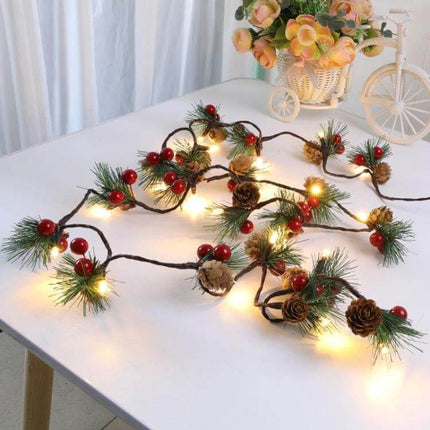 Christmas Pine Needles Light String 2m Warm White Indoor draped on tabletop garland with pinecones, red berries and warm white LEDs