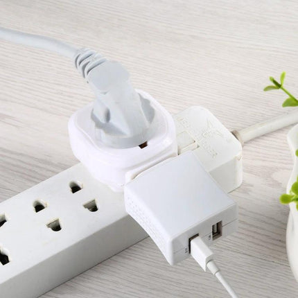 Universal Multi-Plug Travel Adapter for UK and International Use shown plugged into a power strip charging multiple devices