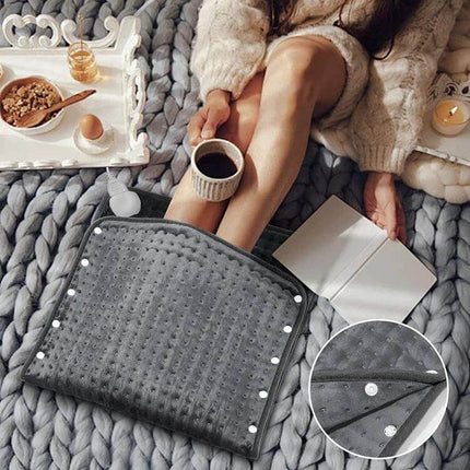 Electric Heating Pad For Waist And Belly Everyday 50x100cm shown in gray crystal velvet warming waist and abdomen while resting with coffee