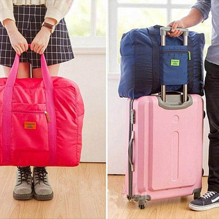 Embellish Foldable Travel Pouch Waterproof Nylon 44x35x19cm shown in pink and navy being carried and stacked on a pink suitcase
