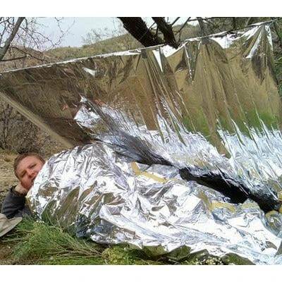 Emergency Blanket Aluminized 140x210 cm For Outdoor Use - person wrapped in reflective emergency blanket under tarp for camping and survival