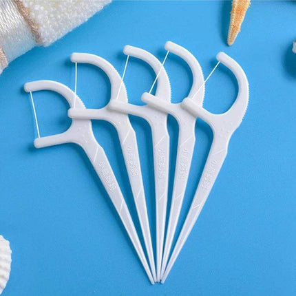 Fawnmum Ultra-Fine Dental Floss Rods, 50 Pcs Per Box, 2 Boxes - five slim white floss picks on blue background with travel-ready compact case