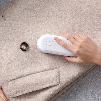 Mijia Mini Portable Lint Remover For Everyday Clothes Care being used on a beige coat to remove fuzz and pills