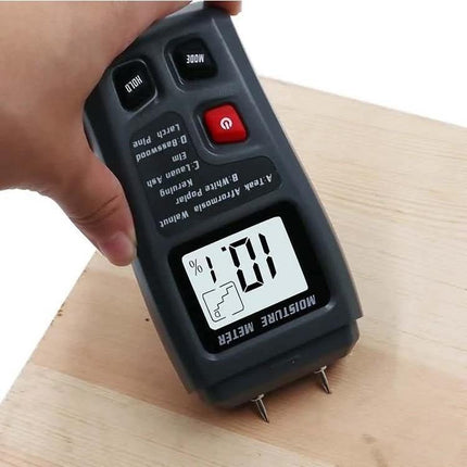 Rechargeable Wood Moisture Tester for Flooring and Carton being used on a wood plank showing digital moisture reading