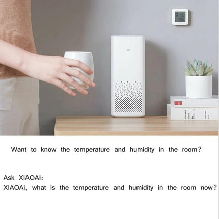Xiaomi Mijia Bluetooth Temperature and Humidity Thermometer for Home Use mounted on wall showing indoor temperature and humidity beside air purifier